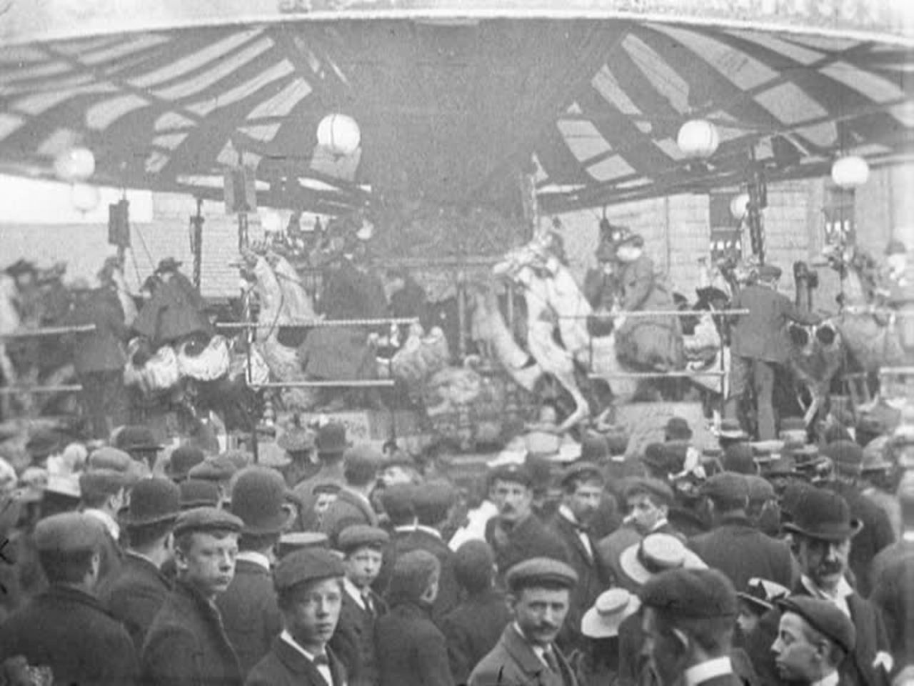 Excited crowds mill around a gorgeous Edwardian carousel where the horses are chickens.
