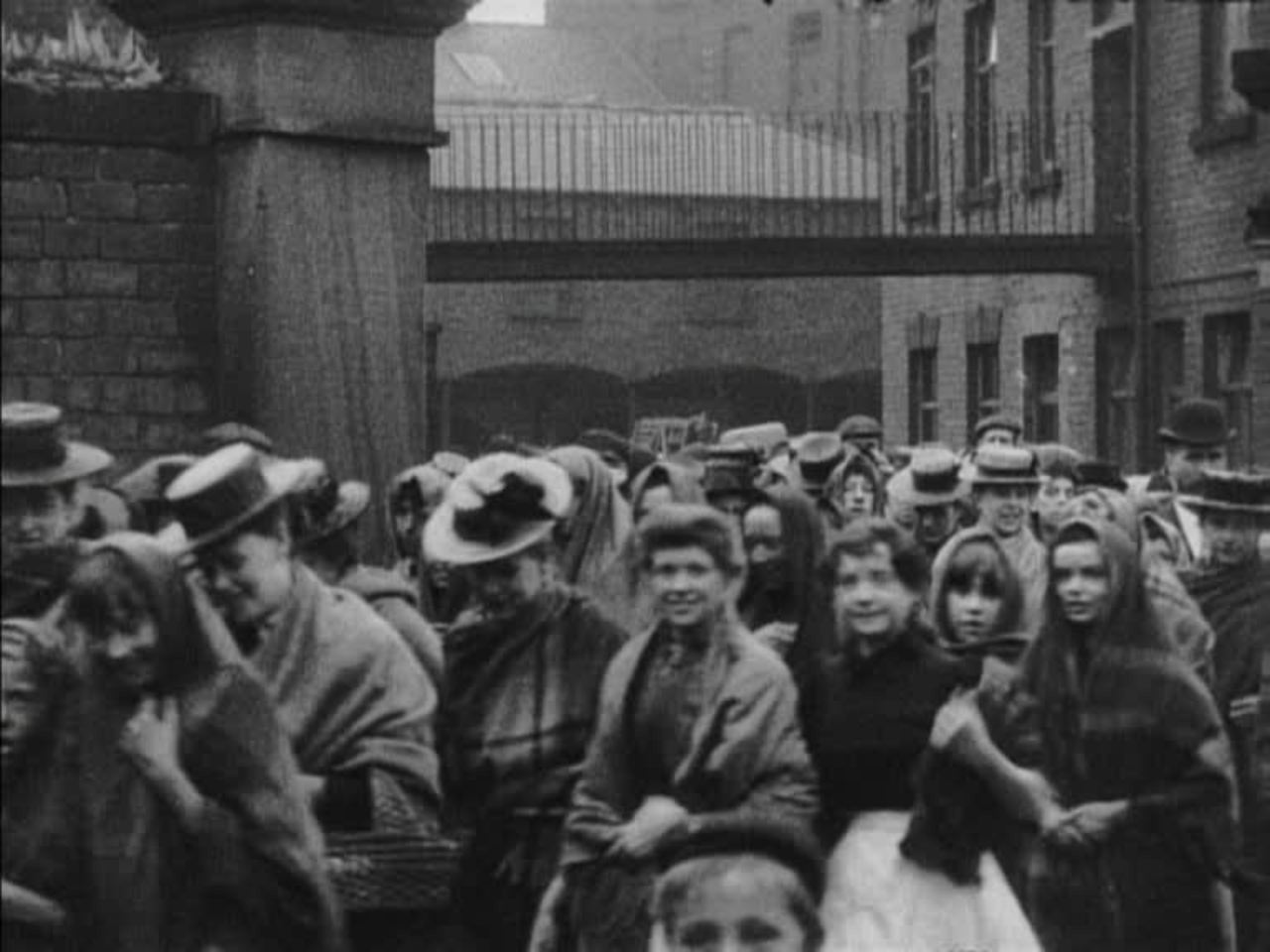 Victorian factory workers head for home, dodging puddles along the way.