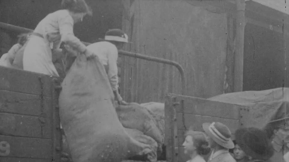 Sprucely dressed women set themselves to lugging tarpaulin and unloading sacks in this WWI newsreel
