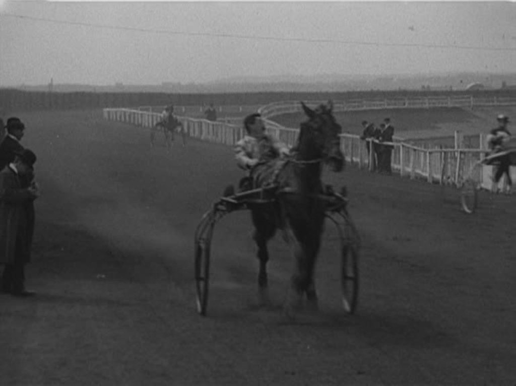 Edwardian spectators and bookies enjoy an exciting day of horse racing.