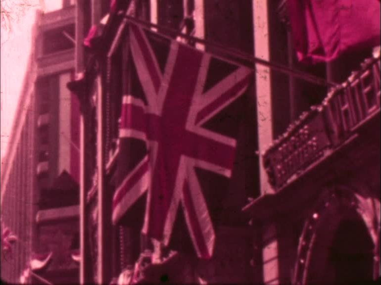Crowds pack the streets of Hong Kong for a stunning procession of dragon dancers, drummers and stilt walkers in celebration of George VI's crowning.